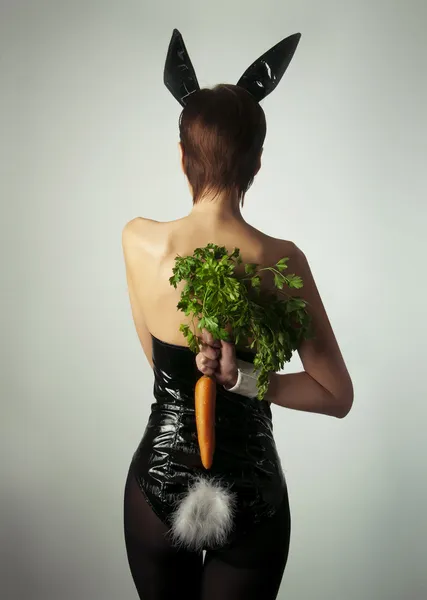 Ein als Kaninchen verkleidetes Mädchen hält eine Karotte hinter sich — Stockfoto