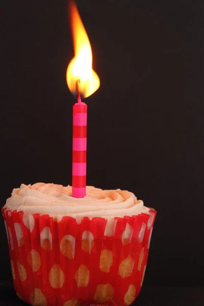 Cupcake mit brennender Kerze Stockbild