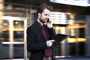 Kırk yaşında iş adamı ayakta bir cep telefonu üzerinde konuşurken modern ofis dışında