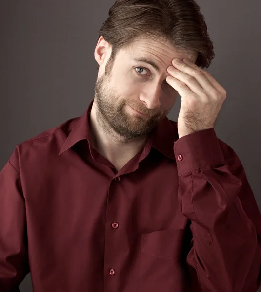 Forty years old ashamed or confused man scratching his head while looking at the camera. Close up portrait on a grey background. — Stock Photo, Image