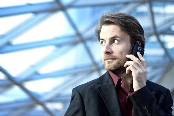 40-jähriger Geschäftsmann steht in modernem Bürogebäude und telefoniert — Stockfoto