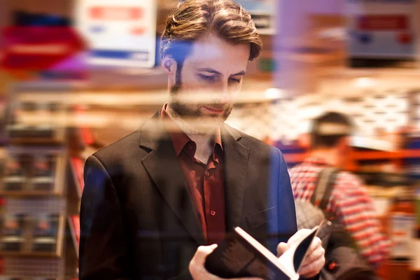 Quarante ans homme élégant debout à l'intérieur de la librairie lire un livre — Photo