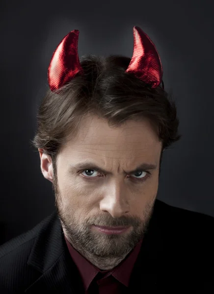 Man in suit with devil horns. Concept of a nasty, cruel, demanding boss or unfair competition in business.