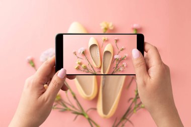 Sarı bale ayakkabılı, akıllı telefonlu bir kadın fotoğraf çekiyor. Sosyal medya için bahar moda trendlerini yakalayan blogcu, etkili ya da stilist. Pastel pembe arkaplan.
