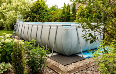 Long, above ground, rectangular, rack (frame) swimming pool outdoor in the garden. Summer holiday (vacation) and recreation.