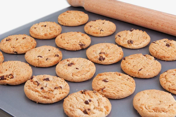 Chocolate chip cookies  on a baking tray with a rolling pin — Stock Photo, Image