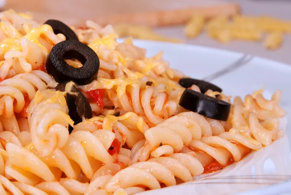 Pasta with tomato, garlic and black olives, sprinkled with chees — Stock Photo, Image