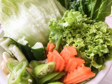 Beyaz kasede bir sürü sebze salatası var.