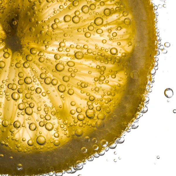 Gros plan de tranche de citron dans de l'eau claire avec des bulles — Photo