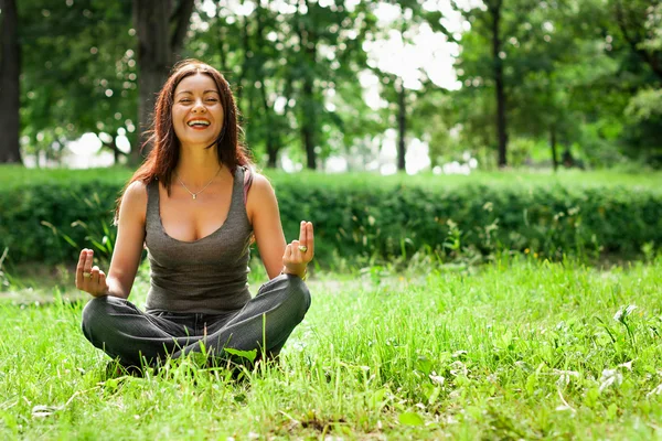 Yeşil çimlerde yoga yapan kadın. — Stok fotoğraf
