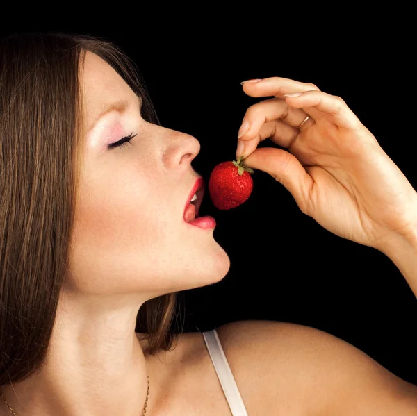 Sexy Woman Eating Strawberry. Sensual Red Lips. Red Nails and Lipstick. Desire. Sexy red Lips with Berry isolated on Black — Stock Photo, Image