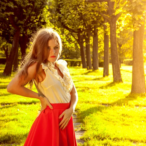 Portrait of young girl in a red skirt in park — Stock Photo, Image