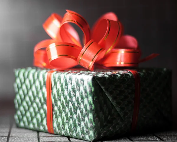 Caja de regalo verde con una cinta roja en primer plano de fondo —  Fotos de Stock