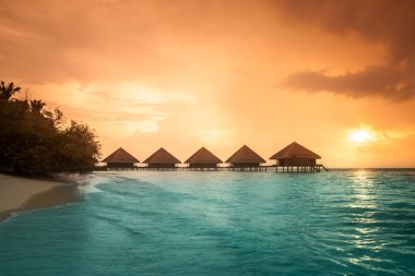 Over water bungalows with steps into amazing green lagoon clipart