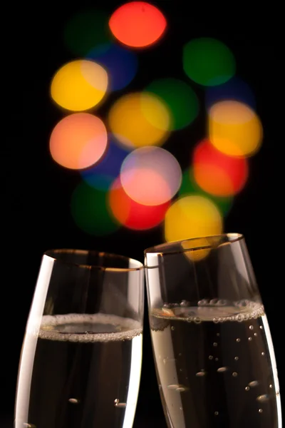 Two glasses of champagne toasting against bokeh lights background — Stock Photo, Image