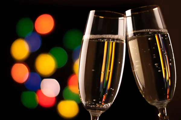 Two glasses of champagne toasting against bokeh lights background — Stock Photo, Image