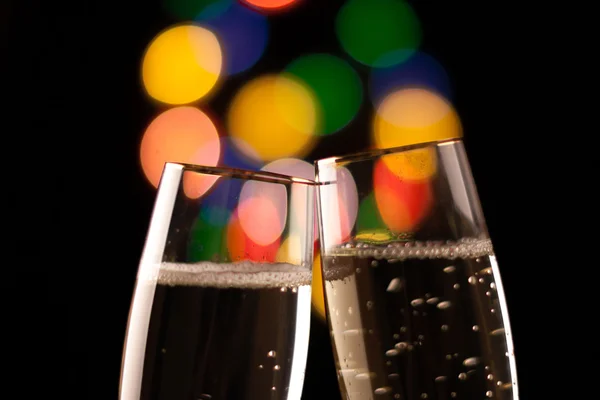Dois copos de champanhe tostando contra bokeh luzes de fundo — Fotografia de Stock