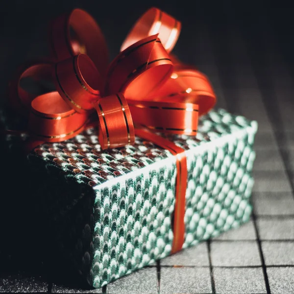 Caja de regalo verde con una cinta roja en primer plano de fondo —  Fotos de Stock