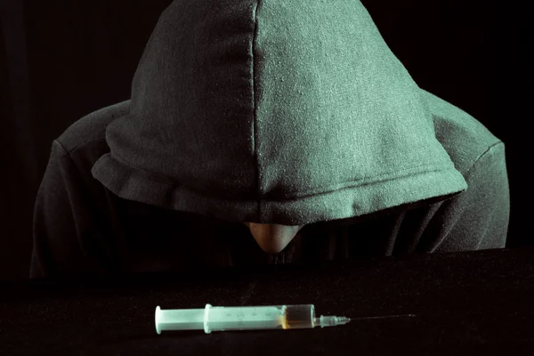 Grunge beeld van een depressief drugsverslaafde kijken naar een spuit en drugs — Stockfoto