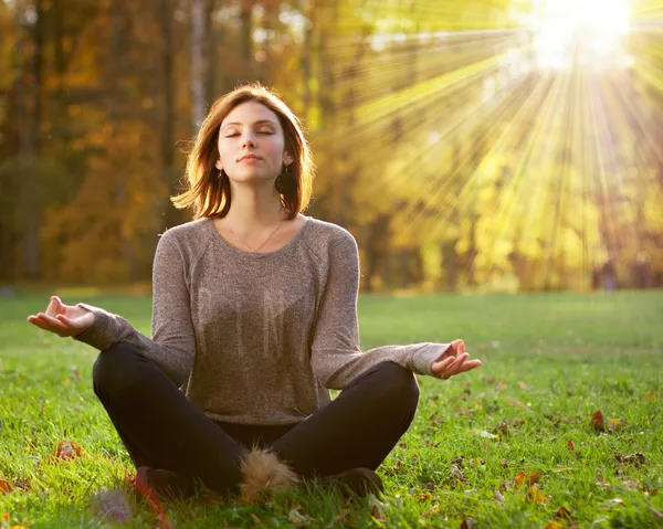 Güz parkında meditasyon yapan güzel bir genç kız.