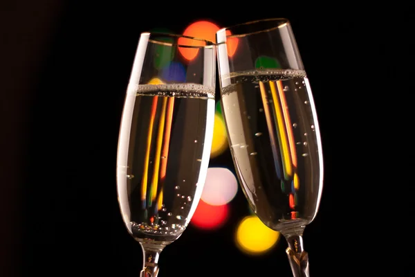 Two glasses of champagne toasting against bokeh lights background — Stock Photo, Image