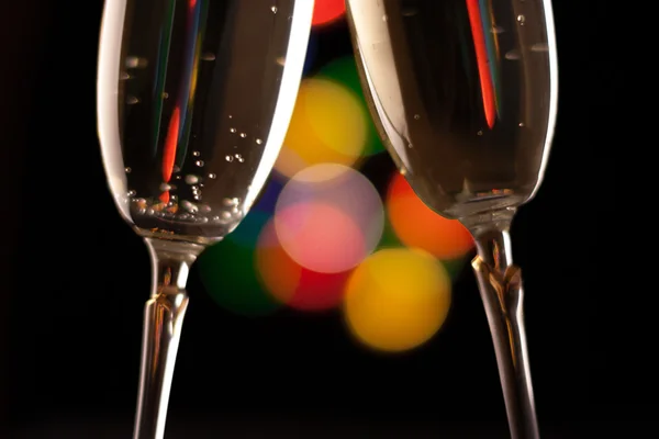 Two glasses of champagne toasting against bokeh lights background — Stock Photo, Image