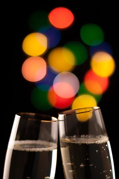 Dois copos de champanhe tostando contra bokeh luzes de fundo — Fotografia de Stock