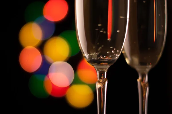 Dois copos de champanhe tostando contra bokeh luzes de fundo — Fotografia de Stock