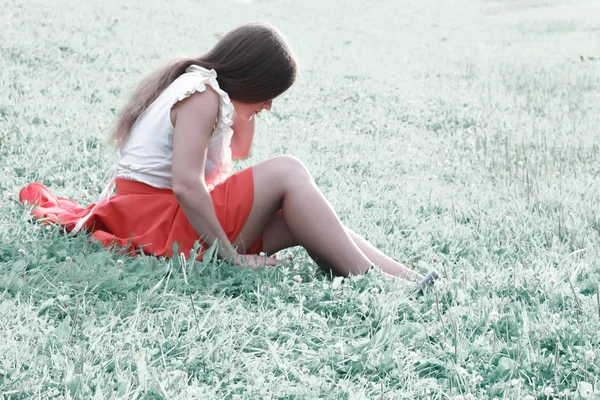 Beautiful brunette sitting on cold field — Stock Photo, Image