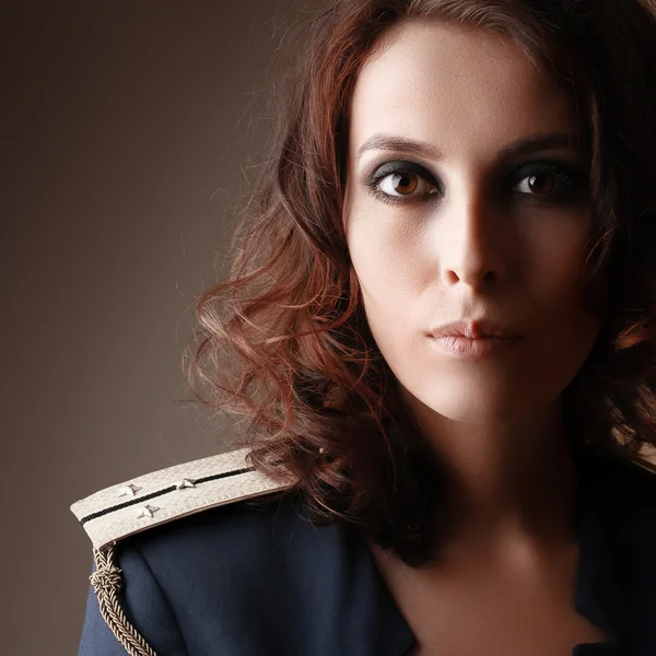 Sexy strict woman with red lips and epaulettes over dark background — Stock Photo, Image