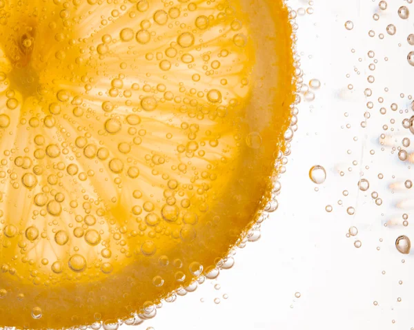 Close-up of lemon slice in clear water with bubbles — Stock Photo, Image