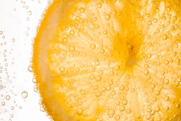 Крупным планом ломтик лимона в чистой воде с пузырьками — стоковое фото