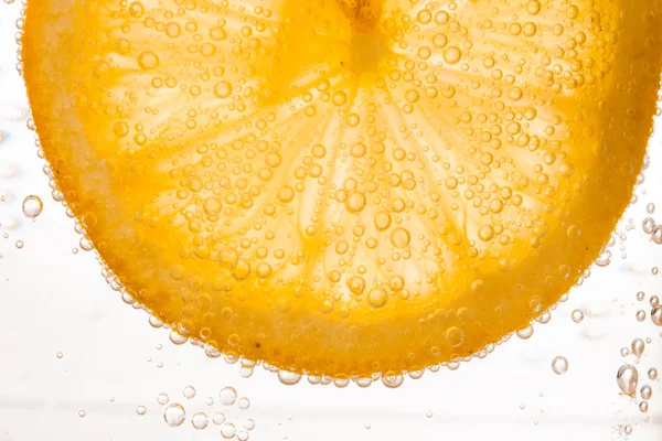 Close-up of lemon slice in clear water with bubbles — Stock Photo, Image