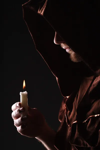 Чарівник в чорній накидці зі свічкою — стокове фото