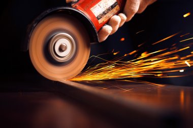 Öğütücüyle metal kesen bir işçi