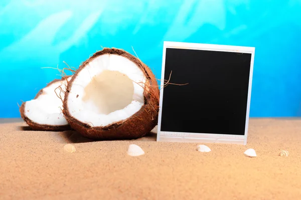 Gehackte Kokosnuss und Fotorahmen im Sand — Stockfoto