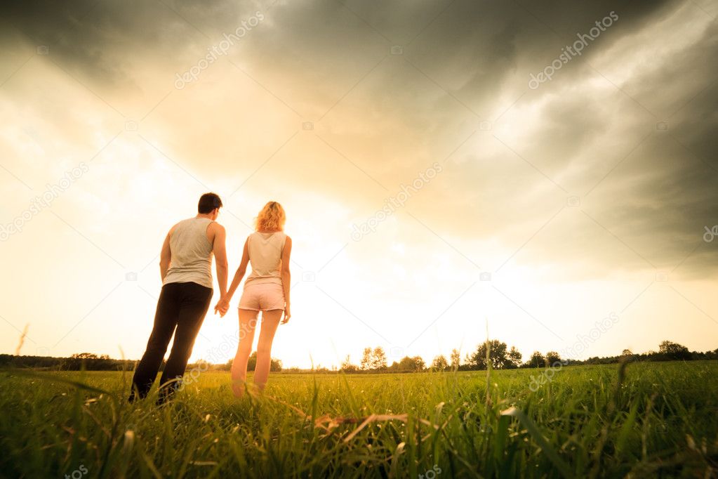 couple walking through the field and holding hands