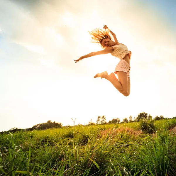 Meisje op het veld springen in de zomer — Stockfoto