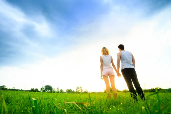 Couple walking through the field and holding hands — Stock Photo, Image