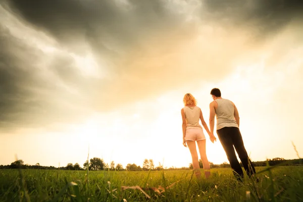 Couple walking through the field and holding hands — Stock Photo, Image