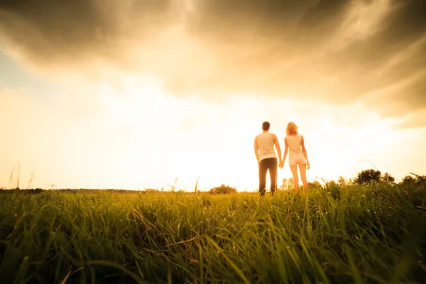 Casal andando pelo campo e de mãos dadas — Fotografia de Stock
