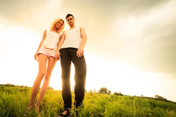 Couple walking through the field and holding hands — Stock Photo, Image