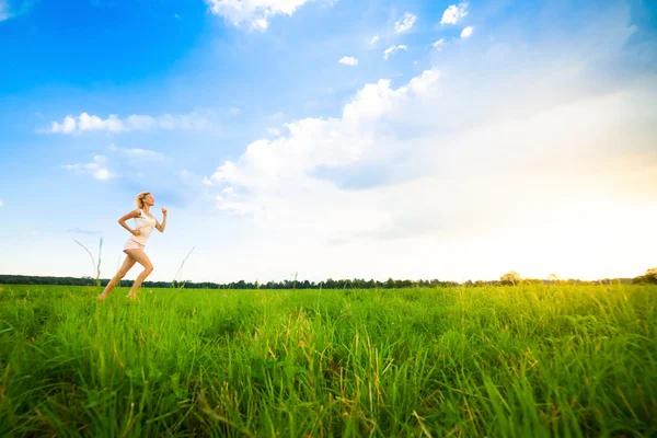 Jovencita corriendo por un camino rural al atardecer — Foto de Stock