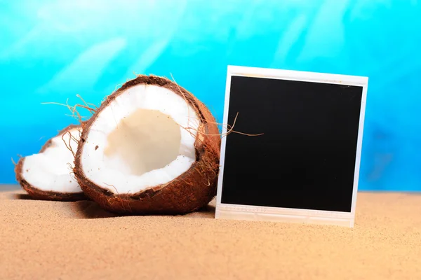 Gehackte Kokosnuss und Fotorahmen im Sand — Stockfoto