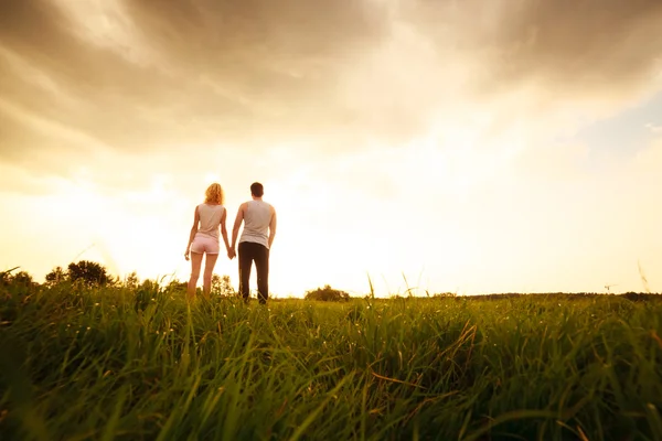 Couple walking through the field and holding hands — Stock Photo, Image