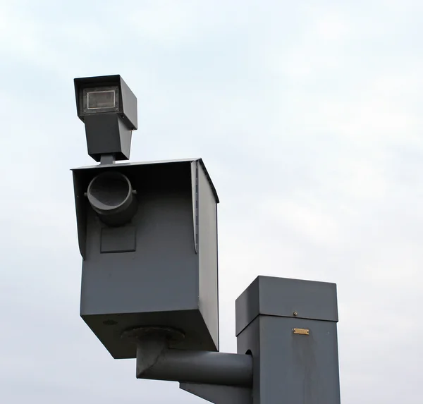 A traffic speed monitoring camera, against a bright blue sky.