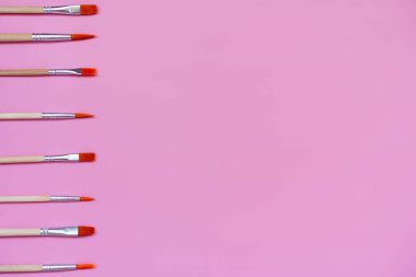 Pembe zemin üzerinde boya fırçaları seti, üst görünüm, düz yatış, metin için boşluk 