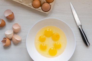 Yemek pişirme süreci, mutfak masasındaki beyaz kasedeki yumurtalar, düz manzara, kahvaltı konsepti. 