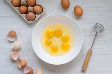 Yemek pişirme süreci, mutfak masasındaki beyaz kasedeki yumurtalar, düz manzara, kahvaltı konsepti. 