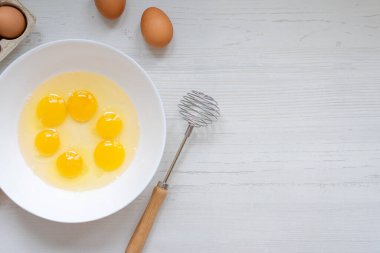 Yemek pişirme süreci, mutfak masasındaki beyaz kasedeki yumurtalar, düz manzara, kahvaltı konsepti. 
